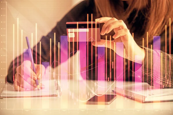 Double exposure of woman on-line shopping holding a credit card and financial graph drawing. Stock market E-commerce concept.