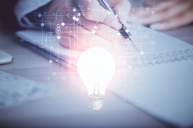 El üstünde tutulan ampul hologramı notlar alıyor. Fikir kavramı. Çift pozlama