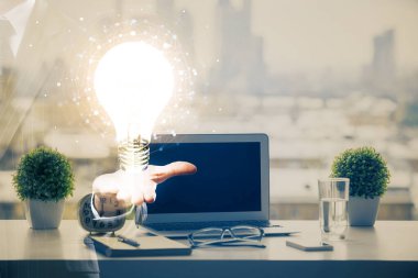 Bilgisayar ofisinde ampul simgesi hologramıyla birlikte. Çifte maruziyet. Fikir kavramı.