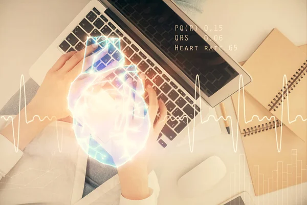 女性双手在电脑和心脏全息图上的双重曝光 顶视图 医学概念 — 图库照片