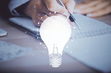 El üstünde tutulan ampul hologramı notlar alıyor. Fikir kavramı. Çift pozlama