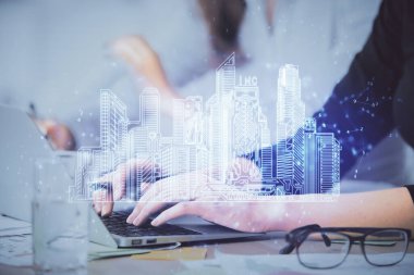 Bilgisayarda yazı yazan kadın elleri ve çizim yapan binalar. Akıllı şehir konsepti.