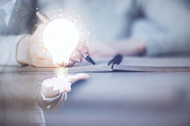 El üstünde tutulan ampul hologramı notlar alıyor. Fikir kavramı. Çift pozlama