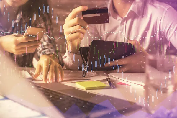 Double exposure of man and woman on-line shopping holding a credit card and forex graph hologram drawing. Stock market E-commerce pay on-line concept.