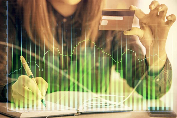 Multi exposure of woman on-line shopping holding a credit card and financial graph drawing. Stock market E-commerce concept.
