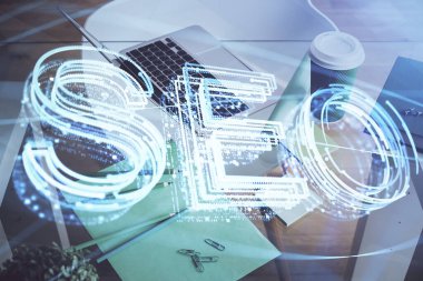 Bilgisayar ve seo çizim hologramı olan bir masanın çifte görüntüsü. Arama optimizasyon kavramı.