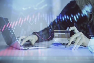 Çevrimiçi alışveriş yapan bir kadının elinde kredi kartı ve mali grafik çizimi tutarken iki kez görüntülenmiş. Borsa E-ticaret kavramı.