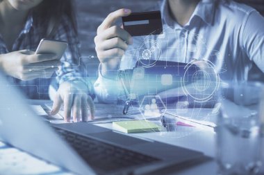 Bir kredi kartı ve sosyal ağ temalı hologram çizimi tutan bir kadın ve erkeğin online alışverişine iki kez maruz kalıyorlar. Bağlayan ve E-ticaret yapan insanlar çevrimiçi konsept üzerinden ödeme yapıyorlar.