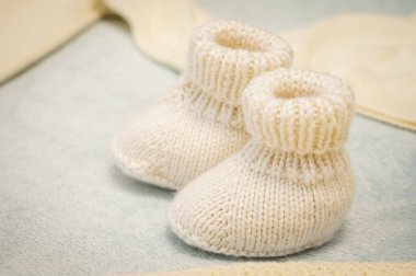 Hafif arka planda, yakın planda, çocuk ayakkabısı giyen bir çocuk için çocuk ayakkabısı örüyordu. Kartpostal.