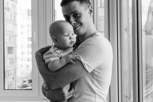 幸せな父親は笑顔で彼の前で彼の腕の中で彼の小さな息子を保持しています 幸せな家族よ — ストック写真