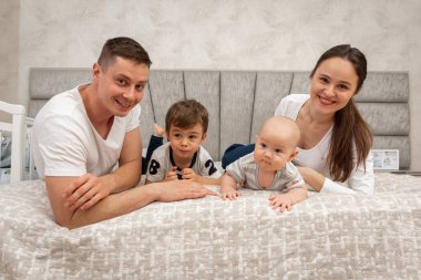 Büyük, güzel bir Ukraynalı, duygusal, neşeli bir aile baba, anne ve iki küçük oğlu yatağın üzerinde, odanın içinde oturuyorlar. Aile kavramı 