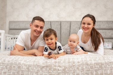 Büyük, güzel bir Ukraynalı, duygusal, neşeli bir aile baba, anne ve iki küçük oğlu yatağın üzerinde, odanın içinde oturuyorlar. Aile kavramı 