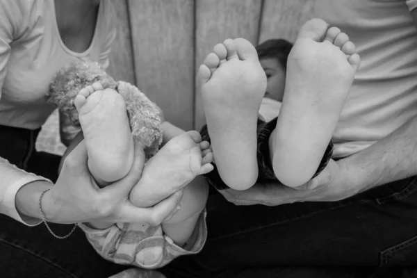 新生婴儿的腿在父母的手中 幸福的家庭观念 妈妈和爸爸抱着孩子的腿 — 图库照片