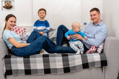 Genç, duygusal, ilginç, neşeli, büyük aile, anne, baba ve oğullar büyük bir yatağa uzanıp kameraya bakıyorlar. Aile tatili