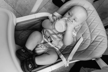 Mutlu küçük çocuk 7-9 ay patates püresi yer, kavanozdan lapa yer, evdeki mutfakta yüksek bir sandalyeyle beslenir. Bebek maması, bebek maması konsepti.