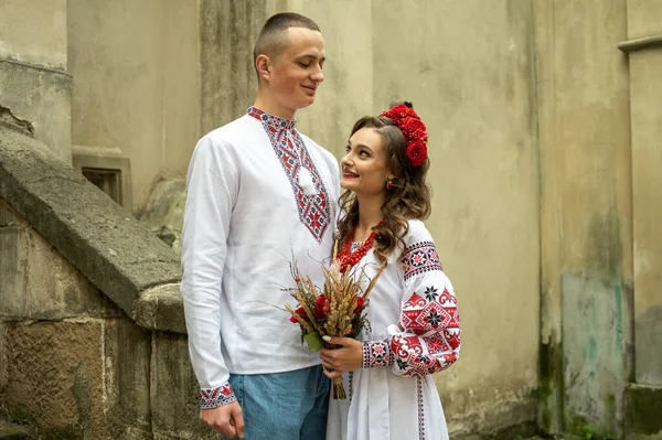Happy young couple in love, family walking in the old city of Lviv in traditional Ukrainian shirts. Young people hug in the old town of Lviv
