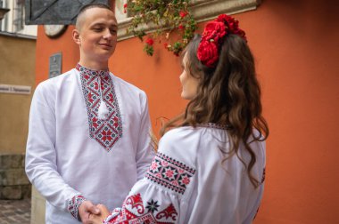 Aşık genç bir çift, Ukrayna 'nın eski şehri Lviv' de kırmızı-turuncu arka planda el ele tutuşan bir aile. Gençler eski Lviv kasabasında sarılıyor 