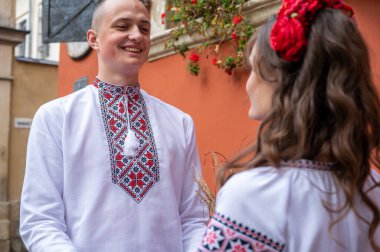 Aşık genç bir çift, geleneksel Ukrayna gömlekleriyle eski şehir Lviv 'de yürüyen bir aile, kırmızı-turuncu arka planda el ele tutuşuyorlar. Gençler eski Lviv kasabasında sarılıyor