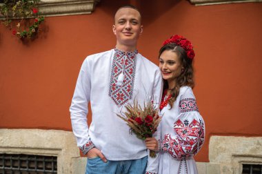 Aşık genç bir çift, Ukrayna 'nın eski şehri Lviv' de kırmızı-turuncu arka planda el ele tutuşan bir aile. Gençler eski Lviv kasabasında sarılıyor 