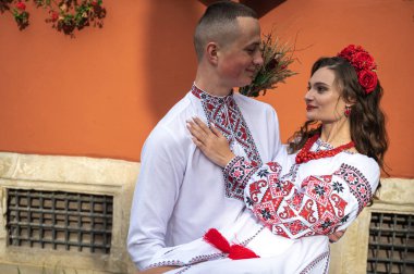 Aşık genç bir çift, Ukrayna 'nın eski şehri Lviv' de kırmızı-turuncu arka planda el ele tutuşan bir aile. Gençler eski Lviv kasabasında sarılıyor 