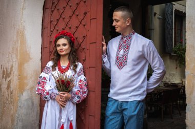 Aşık genç bir çift, Ukrayna 'nın eski şehri Lviv' de kırmızı-turuncu arka planda el ele tutuşan bir aile. Gençler eski Lviv kasabasında sarılıyor 
