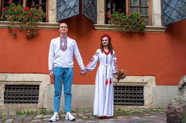 A happy young couple in love, a family walking through the old city of Lviv in Ukrainian embroidered dresses, holding hands. Young people hug in the old town of Lviv