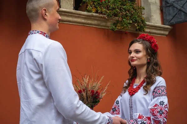 一对心情愉快的年轻夫妇 一家人穿着乌克兰绣花衬衫 手挽手 手挽手穿过乌克兰古老的利沃夫市 在利沃夫老城 年轻人拥抱在一起 — 图库照片