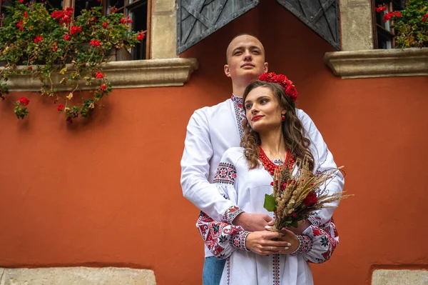 愛の幸せな若いカップル 家族は手を取り合って ウクライナの刺繍のドレスで旧市街のリヴィウを歩く 若い人たちは旧市街で抱擁します — ストック写真