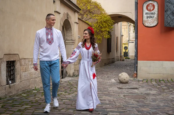 Happy young couple in love, family walking in the old city of Lviv in traditional Ukrainian shirts. Young people hug in the old town of Lviv