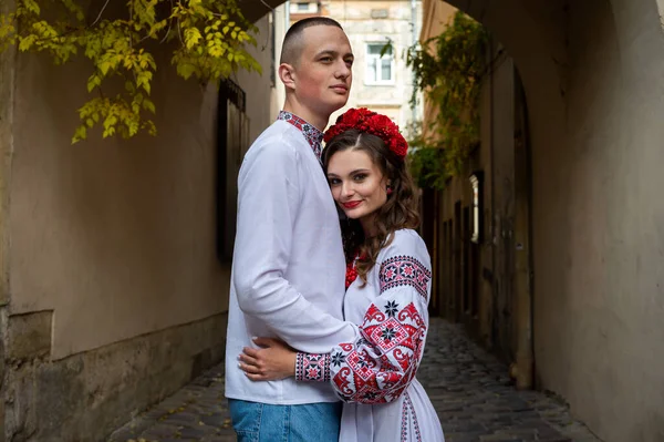 A happy young couple in love, a family walking through the old city of Lviv in Ukrainian embroidered dresses, holding hands. Young people hug in the old town of Lviv