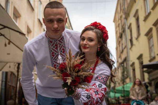 Portrait of a happy young couple in love, a family walking in the old city of Lviv in traditional Ukrainian shirts, walking holding hands. Young people hug in the old town of Lviv