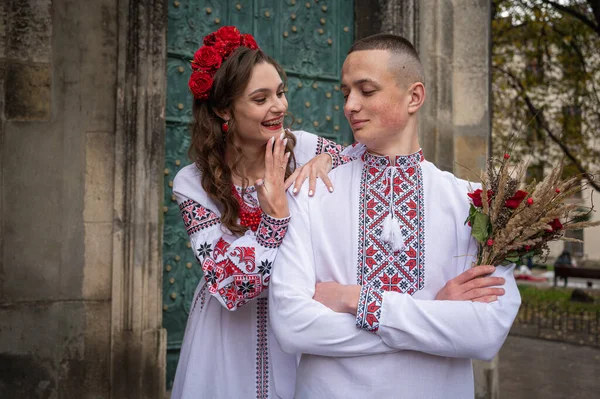 Portrait of a happy young couple in love, a family walking in the old city of Lviv in traditional Ukrainian shirts, walking holding hands. Young people hug in the old town of Lviv