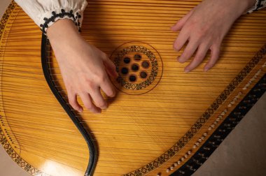 young girl plays ukrainian folk instrument, bandura, hands and strings close up