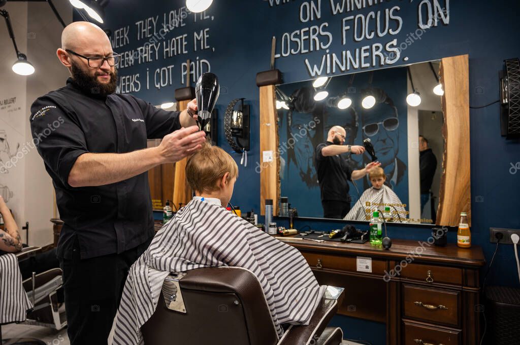 Happy cute fairhaired preschool boy getting a haircut. Children's