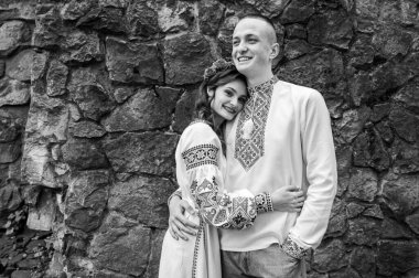 Black and white classic portrait of happy young couple in love, family hugging holding hands in Lviv city wearing traditional Ukrainian shirts. Young people hug in the old town of Lviv