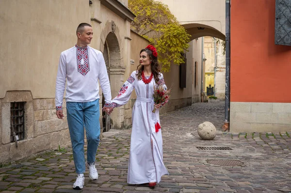 Portrait of a happy young couple in love, a family hugging, holding hands in the city of Lviv in traditional Ukrainian shirts, holding hands. Young people hug in the old town of Lviv