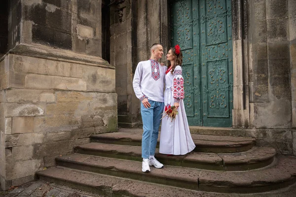 Portrait of a happy young couple in love, a family hugging, holding hands in the city of Lviv in traditional Ukrainian shirts, holding hands. Young people hug in the old town of Lviv
