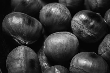 black and white classic photo. Roasted chestnuts on the background of a dark surface. The species of large plan, close