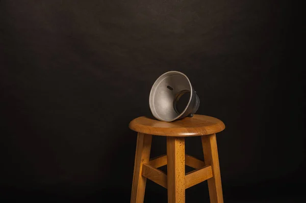 Standard reflector, attachment for studio light on a wooden chair on a dark background. Mount for studio flash with bowens mount.