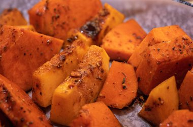 Roasted pumpkin on a light parchment background. Close up view, selective focus. Healthy food
