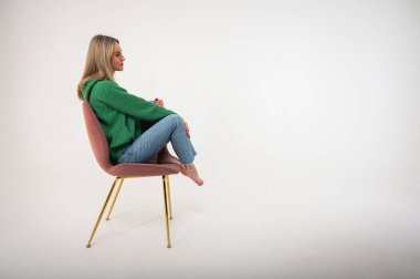 Full length photo of attractive chic businesswoman sitting commanding comfortable chair flirtatious mood empty space wearing jeans and green sweater on isolated white background, place for text