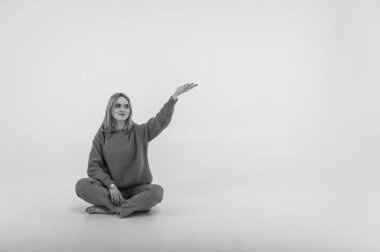 portrait of a young, emotional girl stretching her hands to the camera in a flirtatious mood, gesturing with her hands, empty space, wearing jeans and sweater on an isolated white background