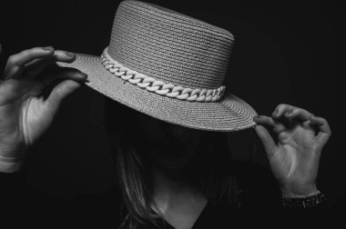 Close-up portrait of a young and beautiful girl making adjustments, adjusting the hat on her head and smiling. Low key