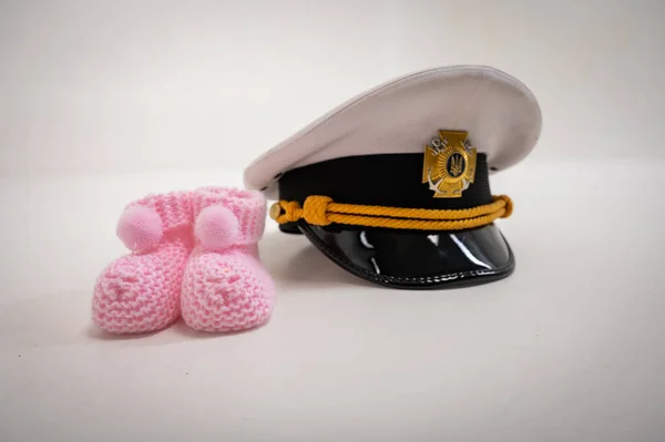 Ukrainian military cap and children's shoes. Waiting for the birth of a child, the father is in the military