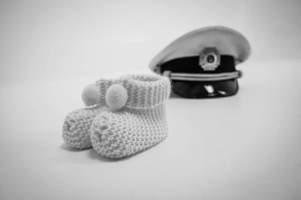 Ukrainian military cap and children's shoes. Waiting for the birth of a child, the father is in the military, Black and white photo