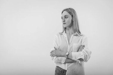 Portrait of a smiling young pretty European woman relaxing while sitting on the floor in jeans and a white shirt, isolated on white background. Place for writing
