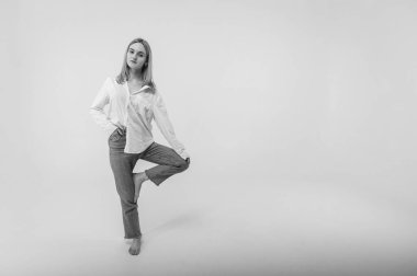 siyah ve beyaz fotoğraf, enerjik aktif genç kız tek ayak üzerinde duruyor elini kaldırdı meditasyon yapıyor, dinleniyor, dinleniyor. Yazma yeri olan hafif arkaplan