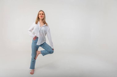 Sportif enerjik aktif genç kız bir bacağının üzerinde duruyor ve bir işaret üzerinde meditasyon yapıyor, rahatlıyor, dinleniyor. Yazma yeri olan hafif arkaplan