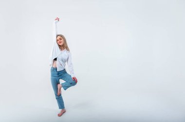 Sportif enerjik aktif genç kız bir bacağının üzerinde duruyor ve bir işaret üzerinde meditasyon yapıyor, rahatlıyor, dinleniyor. Yazma yeri olan hafif arkaplan