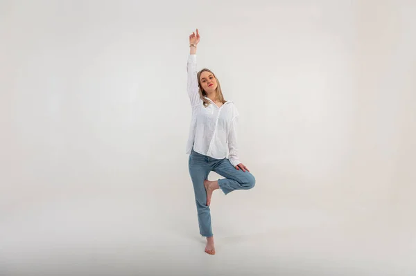 stock image energetic active young girl standing on one leg raised hand up meditating om sign, relaxing, resting. Light background with place for writing